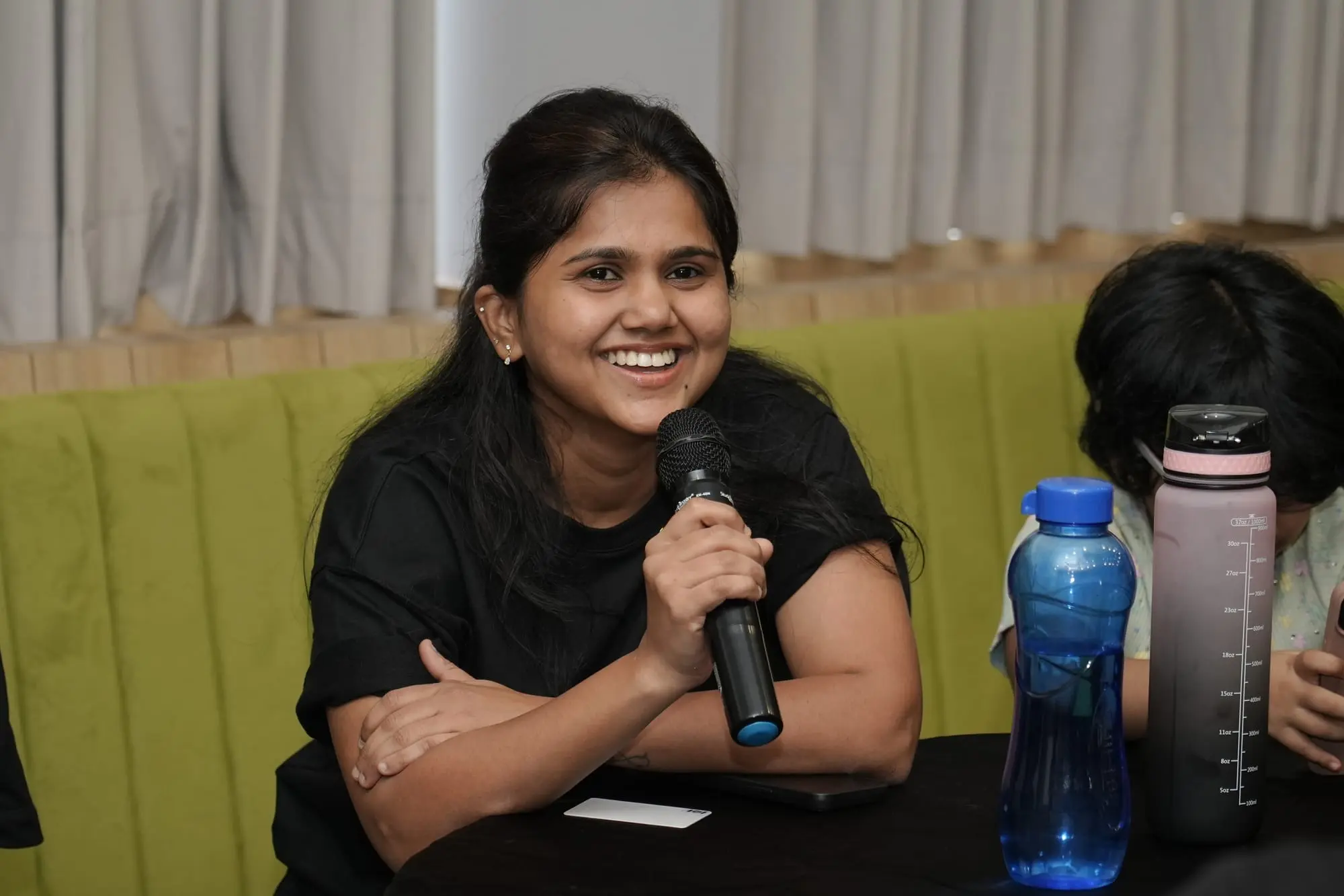 A team member laughing as she speaks into a microphone at the 2026 offsite