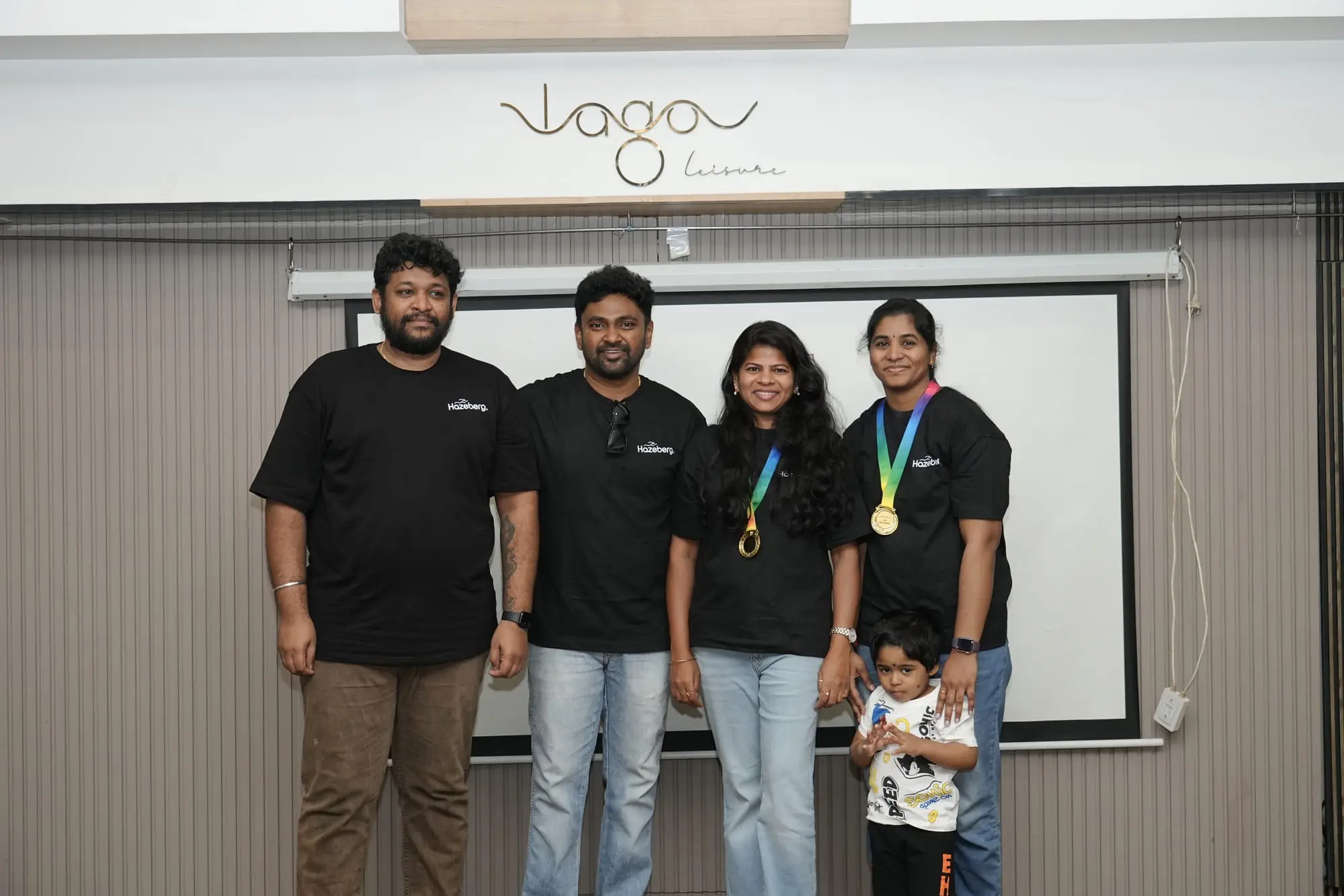 Team members wearing their medals, with a young guest