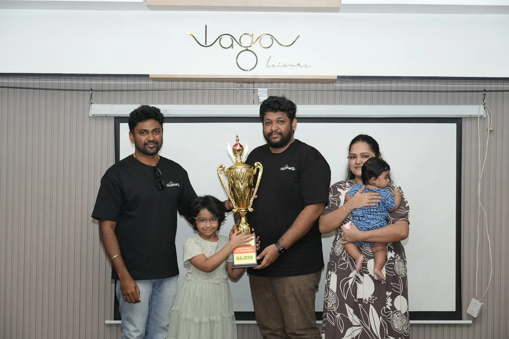 Rajesh holding up his trophy with guests beside him