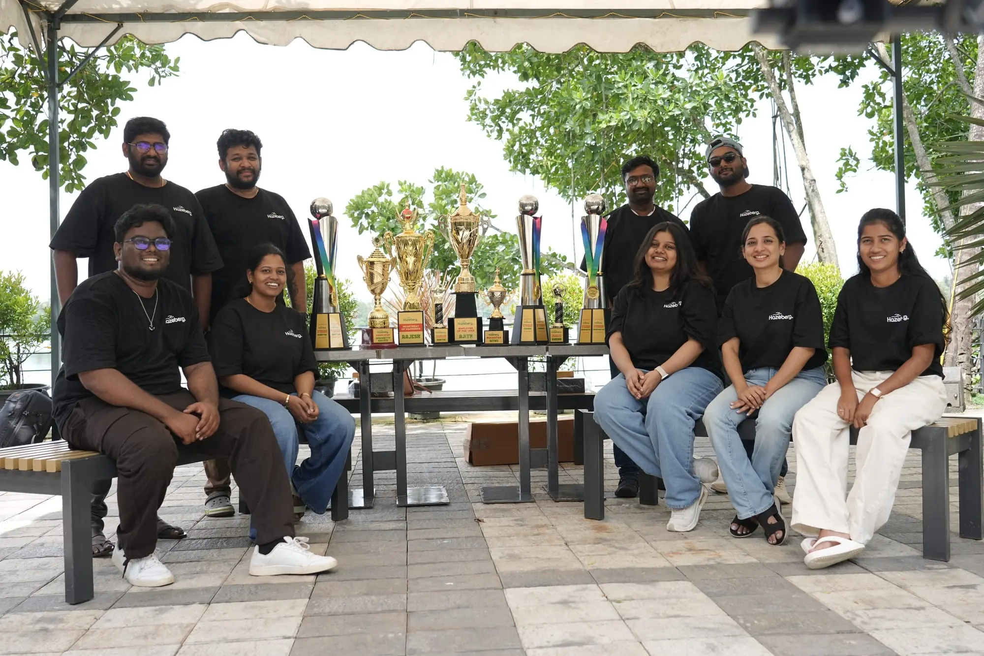 The team outdoors behind a table of trophies